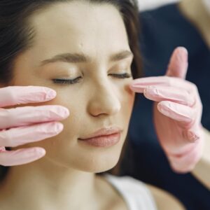 Close-up of a woman with eyes closed receiving facial care in a beauty clinic indoors.